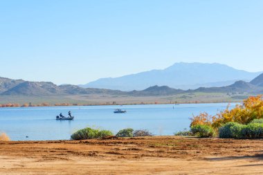 Engebeli tepeler, canlı sonbahar yaprakları ve görkemli uzak dağlarla çerçevelenmiş, huzurlu mavi Perris Gölü 'nde küçük kayıklar süzülüyor..