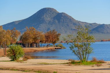 Altın sonbahar yaprakları Perris Gölü 'nün sakin kıyılarını süslüyor, bir dinlenme binası ve açık bir gökyüzünün altında heybetli bir dağ tarafından desteklenen piknik noktaları..