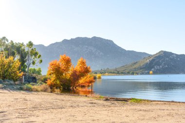 Perris Gölü 'nün sakin sularını çevreleyen canlı sonbahar yeşillikleri, Perris Gölü' nde berrak bir gökyüzü altında heybetli dağlar tarafından desteklenmektedir..