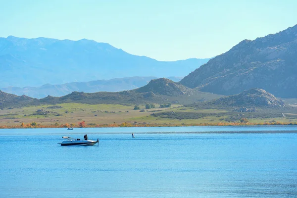 Ziyaretçiler, berrak bir gökyüzünün altındaki engebeli dağlar tarafından çerçevelenmiş Perris Gölü 'nün sakin ve mavi sularında kayıkla gezmenin keyfini çıkarıyorlar..