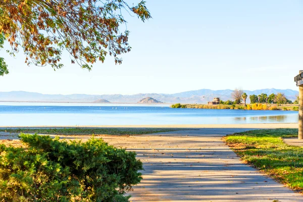 Perris Gölü Eyalet Dinlenme Alanı 'nın sakin suları açık bir gökyüzünün altında uzak dağlarla buluşur. Davetkar bir yol huzur veren doğal güzelliklere götürür..