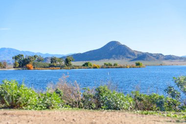 Perris Gölü 'nün sakin mavi suları, yeşil ağaçlı sonbahar renkli bir kıyı şeridi ve Güney Kaliforniya' da berrak bir gökyüzünün altında büyük bir dağ tarafından çerçevelenmiş beyaz şamandıralarla doludur..
