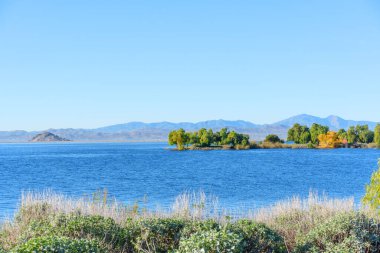 Geniş mavi su kütlesi Perris Eyaleti dinlenme bölgesinde berrak bir gökyüzünün altındaki kurak dağlarla çelişiyor..