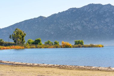 Perris Gölü 'nün sakin suları canlı sonbahar yapraklarıyla buluşur. Engebeli granit dağlar California 'da berrak bir gökyüzünün altında görkemli bir şekilde yükseliyor..