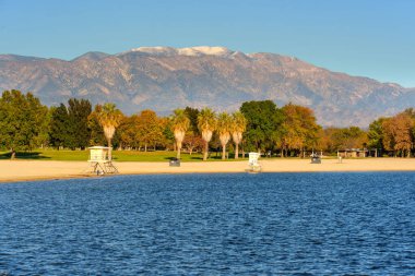 Perris Gölü 'nün berrak mavi suları parlak bir sonbahar yeşilliği ve uzak kar tozlu San Bernardino Dağları' nı parlak bir gökyüzü altında öngörüyor..