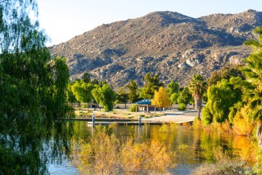 Titrek yapraklar Perris Gölü 'nün sakin sularını çerçeveler, küçük bir rıhtım ve piknik barınakları yansıtır, muhteşem kayalık dağlar ötesinde.