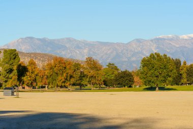 Sonbahar ağaçlarının, Perris Gölü dinlenme bölgesinde açık mavi bir gökyüzünün altında kar tozuyla kaplı uzak dağlara uzandığı geniş bir alan..