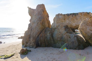 El Matador Eyalet Sahili 'ndeki kumtaşı yığınları çarpıcı bir şekilde kumlu sahili kaplıyor Pasifik Okyanusu dalgaları üzerinde parlayan parlak güneş ışığı..