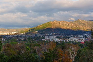 Riverside, California 'nın panoramik manzarası. Dağlar, şehir manzarası ve dramatik gökyüzü altın saat ışığı altında çekildi..