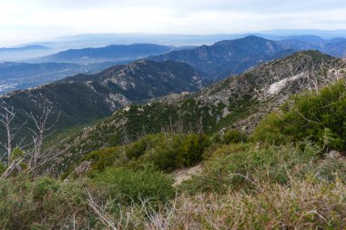 San Gabriel Dağları 'ndaki yüksek bir tepeden Güney Kaliforniya' daki sisli bir şehir vadisine doğru engebeli tepelerin ve şapelin üzerinden manzarayı süpürüyor..