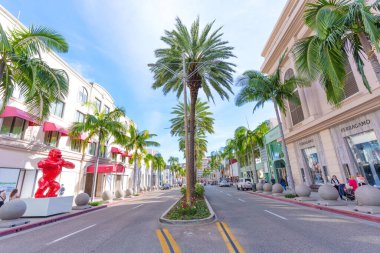 Beverly Hills, California - 21 Ocak 2026: Lüks alışveriş caddesinde Gucci ve Ferragamo gibi parlak palmiye ağaçları ve göz alıcı kırmızı goril heykelleri bulunan lüks markalar yer almaktadır..