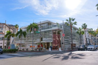 Beverly Hills, California - 21 Ocak 2026: Louis Vuitton 'un palmiye ağaçlı modern mağazası, Beverly Hills' te sokak işaretleri, trafik ve yayaların yer aldığı bir kavşakta duruyor..
