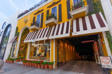 Beverly Hills, California - 21 Ocak 2026 Rodeo Drive 'daki ikonik sarı Bijan binası, çizgili tenteleri, kırmızı çiçekleri ve garajının özel girişini gösteriyor..