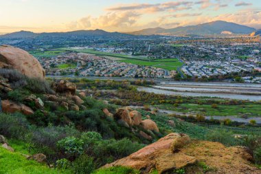 Riverside City Panorama ve Santa Ana Nehri Vadisi Güney Kaliforniya 'da sıcak bir günbatımında Rubidoux Dağı' nın kayalık yamaçlarından görülüyordu..