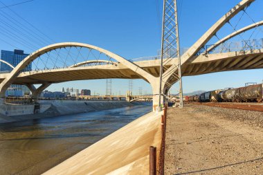 Los Angeles, Kaliforniya - 10 Ocak 2026 Modern Beton Altıncı Cadde Viaduct zarif bir şekilde Los Angeles Nehri üzerinde kavis çiziyor, berrak mavi gökyüzü altında yük vagonları ile yan yana geliyor..