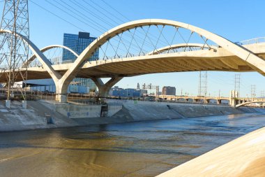 Los Angeles, California - 10 Ocak 2026: 6. Cadde Viaduct 'un beton kemerleri Los Angeles Nehri' ni görkemli bir şekilde geçiyor, kentsel yapılar ve açık mavi bir gökyüzü ile çevrili..