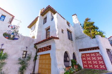 İspanyol Koloni mimarisi, beyaz sıva, kırmızı kiremit çatılar, kemerli girişler ve desenli garaj kapıları içeren ayırt edici Santa Barbara evi..