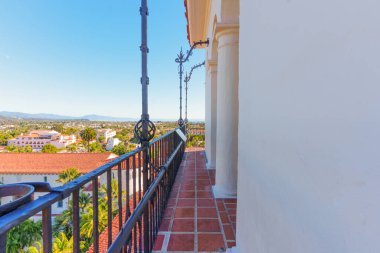 Klasik İspanyol tarzı bir balkondan güzel bir manzara. Terasotta zemini ve işlenmiş demir parmaklıkları var. Santa Barbara 'nın çatılarına ve kıyılarına bakıyor..