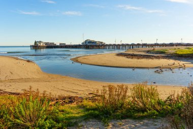 Pasifik Okyanusu 'na doğru akan sakin sularıyla Santa Barbara sahilindeki kıyı lagününün geniş manzara manzarası ve uzakta duran ikonik Stearns Rıhtımı..