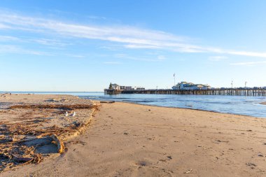 Santa Barbara 'daki Stearns Rıhtımı' nın klasik manzarası, kumlu bir plaj ve güzel mavi bir gökyüzünün altında sürüklenen dallar..