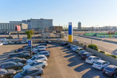 Los Angeles, Kaliforniya - 12 Ocak 2026: Los Angeles, Kaliforniya 'da açık mavi gökyüzü altında sayısız araç ve ofis binasının yer aldığı LAX havaalanı yakınlarındaki park yeri manzarası.