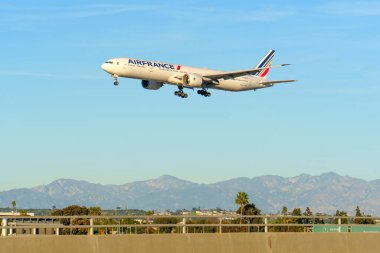 Los Angeles, California - 12 Ocak 2026: Air France Boeing 777-300ER geniş gövdeli jeti Los Angeles Uluslararası Havaalanı 'na manzara dağları ve palmiye ağaçları ile iniş yaptı..
