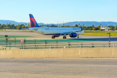 Los Angeles, California - 12 Ocak 2026: Modern Delta Airlines Airbus A321 Los Angeles Uluslararası Havalimanı 'nın güneşli pisti boyunca zarif taksiler.