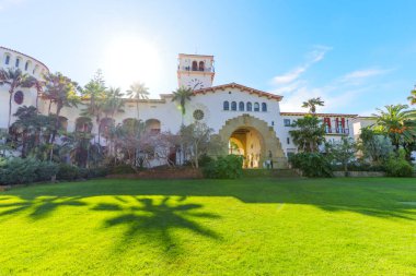 Santa Barbara, Kaliforniya - 29 Aralık 2025: Santa Barbara 'nın tarihi adliyesi parlak mavi bir gökyüzü altında ışıldıyor, İspanyol sömürgeci canlandırma mimarisi yemyeşil çimlerde ışıkla güçleniyor.