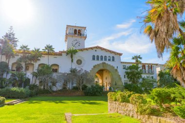 Santa Barbara, Kaliforniya - 29 Aralık 2025: Karmaşık Koloni Diriliş mimarisi ve ikonik saat kulesi ile tarihi Santa Barbara İlçe Mahkemesi, yeşil bahçelerin ortasındaki büyük kemer yolu