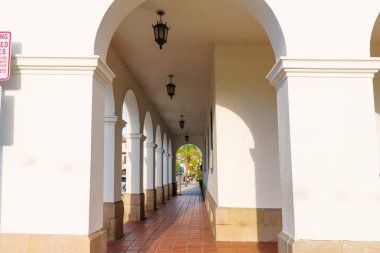 Santa Barbara, California - 29 Aralık 2025 Santa Barbara Belediye Binası 'ndaki sakin kemerli koridorun arka arkaya gelen kemerlerden süzülen ışıkla derin perspektif çekimi.