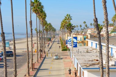 Okyanus Kenarı, Kaliforniya - 17 Aralık 2025: Okyanus kıyısında parlak bir gökyüzü altında kumlu sahil ve okyanus boyunca uzanan yüksek palmiye ağaçları ile ünlü kıyı yolu.