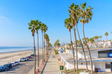 Oceanside, California - 17 Aralık 2025: Iconic palmiye çizgili Okyanus Bulvarı, Kaliforniya, geniş kumlu sahile paralel uzanır ve parlak mavi gökyüzü altında ışıl ışıl okyanus.