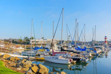 Okyanus Kenarı, Kaliforniya - 17 Aralık 2025 Oceanside Limanı 'nda çok sayıda yelkenli ve yatla dolu hareketli bir sahne, yansımaları suda, uzak bir deniz feneriyle parıldıyor..