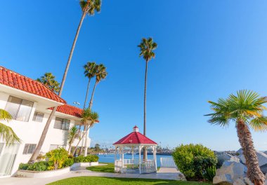 Kırmızı çatıları olan beyaz binalar, yüksek palmiye ağaçları, ve yeşil çimlerde oturan büyüleyici beyaz çardak, Oceanside, California 'da güneşli bir limana bakıyor.