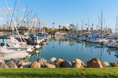 Okyanus Kenarı, Kaliforniya - 28 Aralık 2025: Okyanus Kıyısı 'nın geniş perspektifi, kayalar ve çimenler tarafından çerçevelenmiş sakin suda geniş bir dizi tekne ve onların yansımalarını sergiliyor.