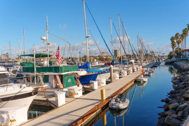 Okyanus Kenarı, Kaliforniya - 28 Aralık 2025: Okyanus kıyısında açık bir gökyüzü altında Amerikan bayrağı dalgalanması da dahil olmak üzere çeşitli teknelerin yer aldığı canlı bir marina limanının yakın görüntüsü.