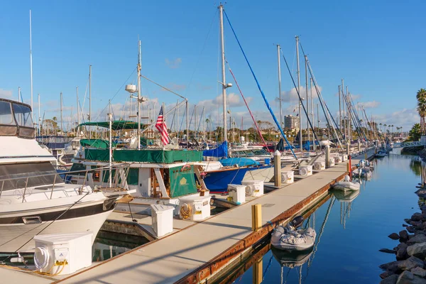 Okyanus Kenarı, Kaliforniya - 28 Aralık 2025: Amerikan bayrağını gururla dalgalandıran bir yatın diğer teknelerle birlikte Oceanside Marina 'ya yanaşması, durgun suya yansıması..