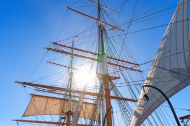 Tahta direkler ve tarihi bir yelkenli gemisinin kompleks donanımı San Diego, Kaliforniya 'da parlak mavi bir gökyüzüne kadar uzanıyor. Güneş ışınları iplerden parlıyor..