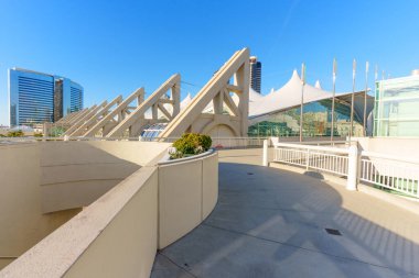 San Diego Kongre Merkezi, açık mavi gökyüzü ve şehir siluetine karşı beyaz yelken benzeri çatıları ve beton kirişleri olan ikonik mimari tasarımı sergiliyor.