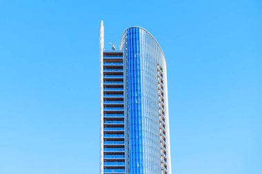 San Diego, California - 30 Aralık 2025: Eğri, modern cam ve çelik gökdelenin tepesine yakın mimari detay San Diego 'da katı, açık mavi bir gökyüzüne karşı.