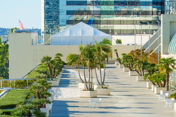 Çatı katında güneşli bir açık hava meydanı. San Diego, Kaliforniya şehir merkezindeki tropikal palmiye ağaçları, beyaz kafe masaları ve modern mimari içeriyor..