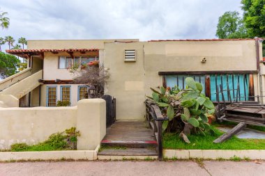 Eski ahşap arabalı Adobe tarzı bina, büyük dikenli armut kaktüsü, ve tarihi güneybatı mimarisi Old Town San Diego, California 'da bulutlu bir gökyüzü altında.