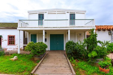 San Diego, California - 30 Aralık 2025: Eski San Diego Şehir Tarihi Parkı 19. yüzyıl mimarisi, beyaz ahşap cepheler, deniz mavisi kapılar, yemyeşil bahçe düzenlemeleri ile yeniden inşa edildi.