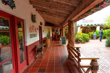 San Diego, California - 31 Aralık 2025: Eski Şehir 'de fayanslı yürüyüş yolu, taşralı ahşap kirişlerin altında büyüleyici özel dükkanların önünden geçerek canlı, güneşli bir avluya açılıyor..