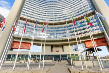 Viyana, Avusturya - 25 Şubat 2026: Viyana Uluslararası Merkezi, UNO Şehri 'nin modern kıvrımlı cephesi, açık mavi gökyüzü altında dalgalanan bir dizi uluslararası bayrakla çevrilidir..