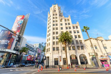 Los Angeles, Kaliforniya - 29 Ocak 2026: Tarihi beyaz Art Deco kulesi, Los Angeles 'taki Hollywood ve Highland kavşağındaki modern oyun afişleriyle çelişiyor.