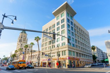 Los Angeles, Kaliforniya - 29 Ocak 2026: İllüzyonlar Müzesi 'ne ev sahipliği yapan modern mimari, yanından geçen bir okul otobüsüyle güneşli bir Hollywood kavşağında duruyor..