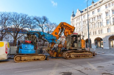 Viyana, Avusturya - 24 Şubat 2026: Viyana 'da kentsel kalkınma ve altyapı onarımı için tarihi mimarinin yanındaki kaldırımlı sokağa park etmiş ağır kazıcıları izledik.