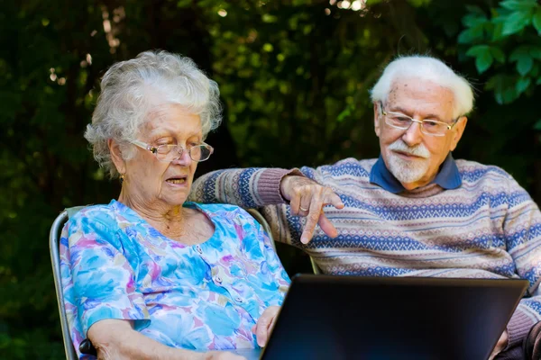 Casal de idosos se divertindo com o laptop ao ar livre — Fotografia de Stock