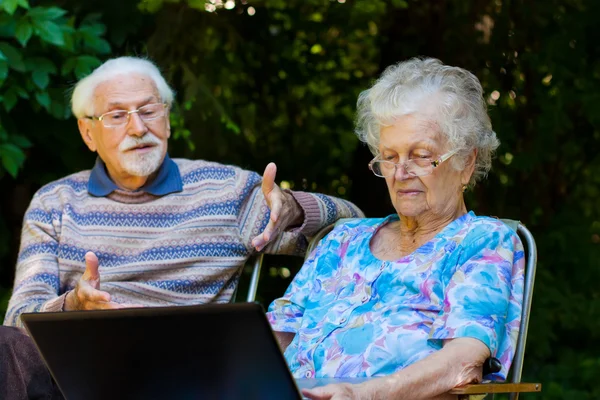 Elderly couple having fun with the laptop outdoors